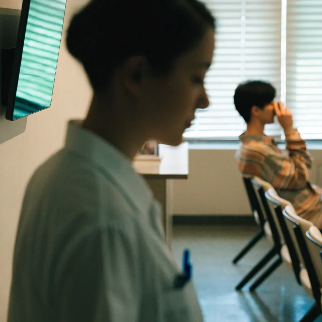 Clinic receptionist arranging appointments at a desk in a bright waiting area